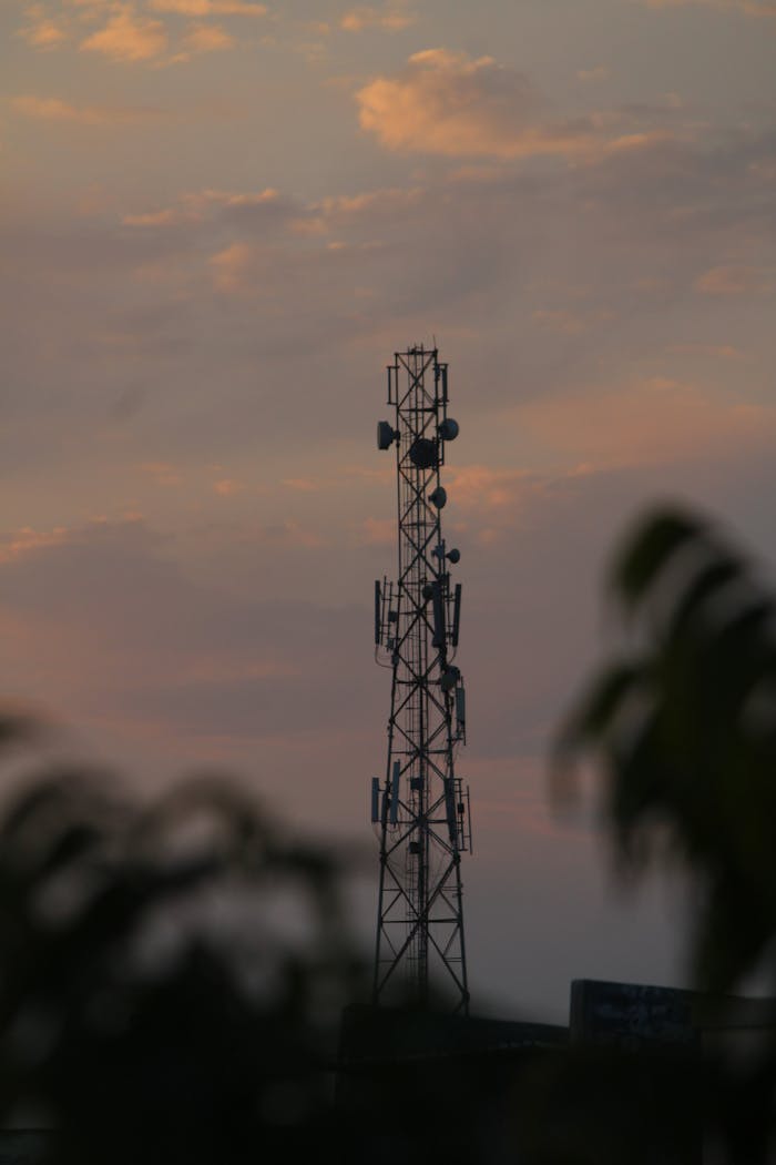 A silhouetted cell tower against a colorful sunset sky, capturing modern communication technology.